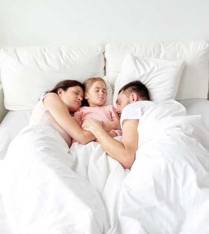 happy-family-sleeping-in-bed-at-home-P9VXT25-1500×1000