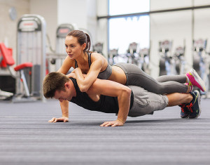 fitness, sport, training, teamwork and lifestyle concept - smiling couple doing push-ups in the gym