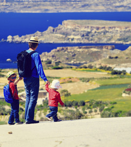 father with two kids walking on scenic road, family travel